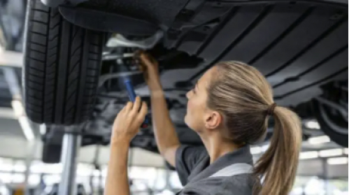 Technician inspecting underside of car